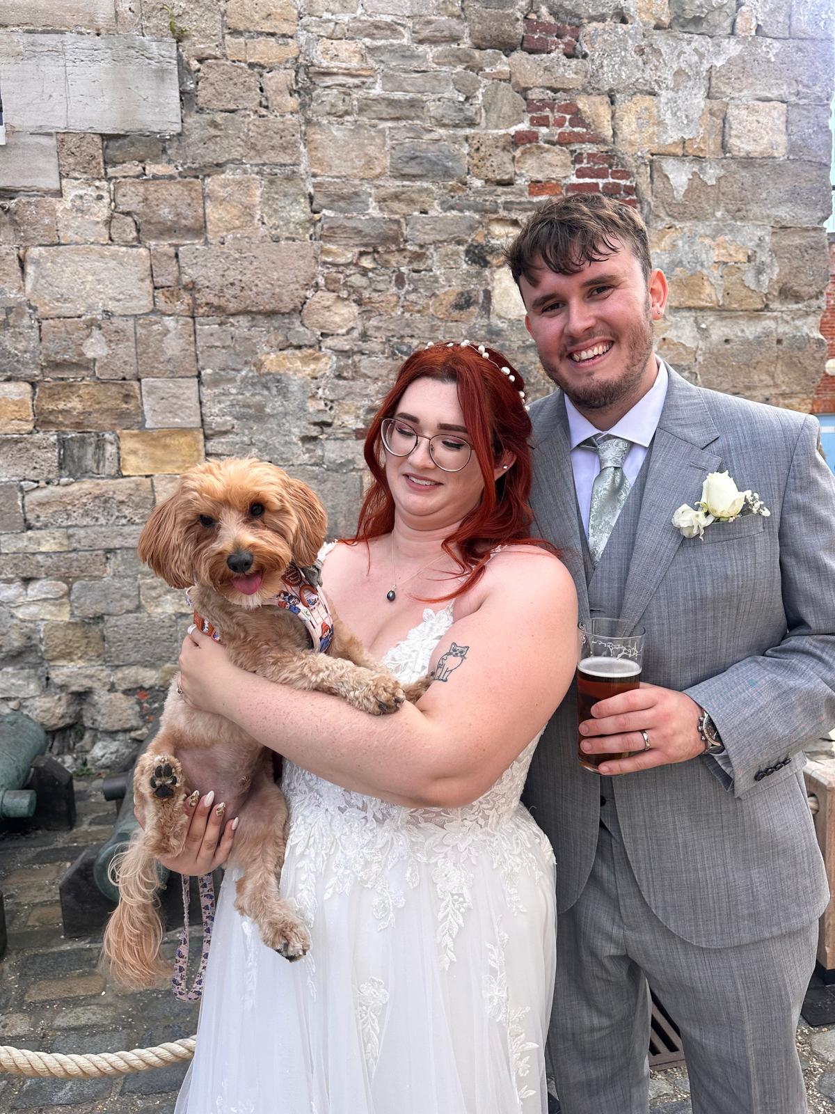 happy couple with their dog at their wedding